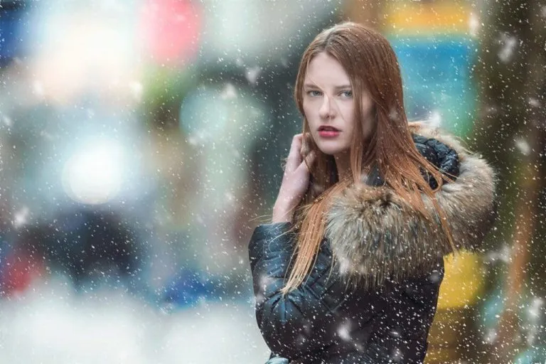 雪の降る中で黒のコードを着ている碧眼で若いロシア人女性の写真